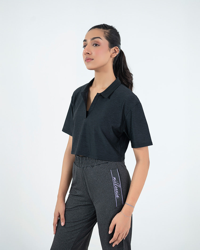 Woman wearing a black crop top with sleeves and dark gray pants on a white background.