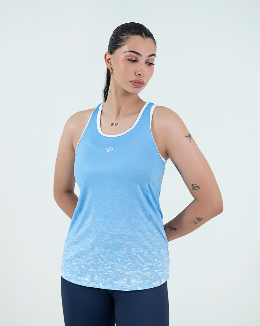 Womens Gym Wear Tank Top Online In Pakistan, featuring a light blue design with a white logo, worn by a woman against a simple background.