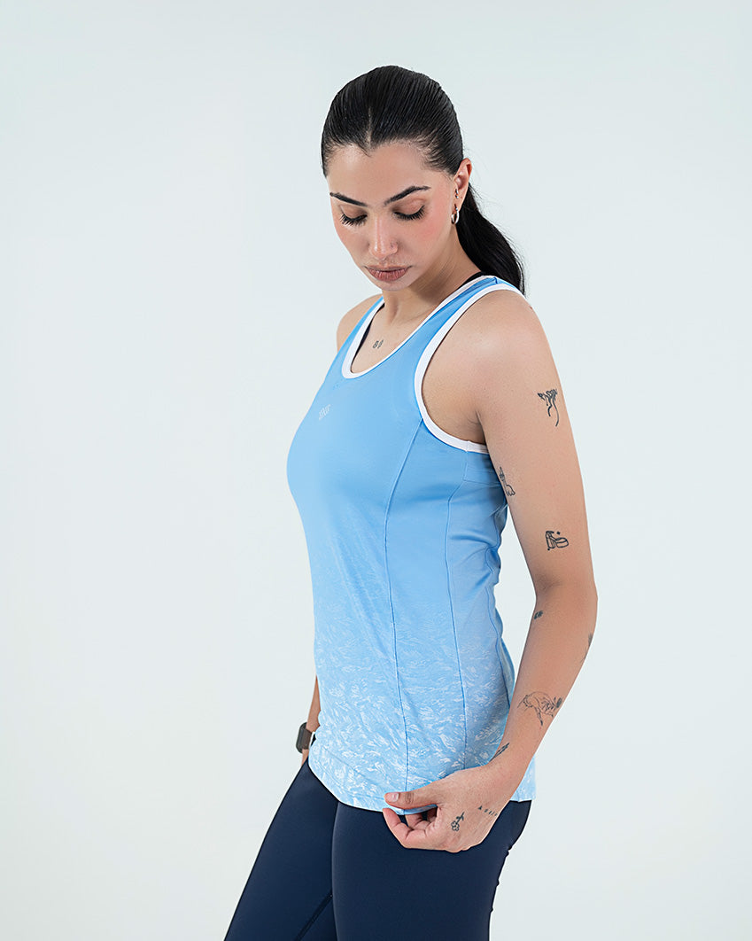 Womens Gym Wear Tank Top Online In Pakistan, featuring a light blue design with a white logo, worn by a woman against a simple background.