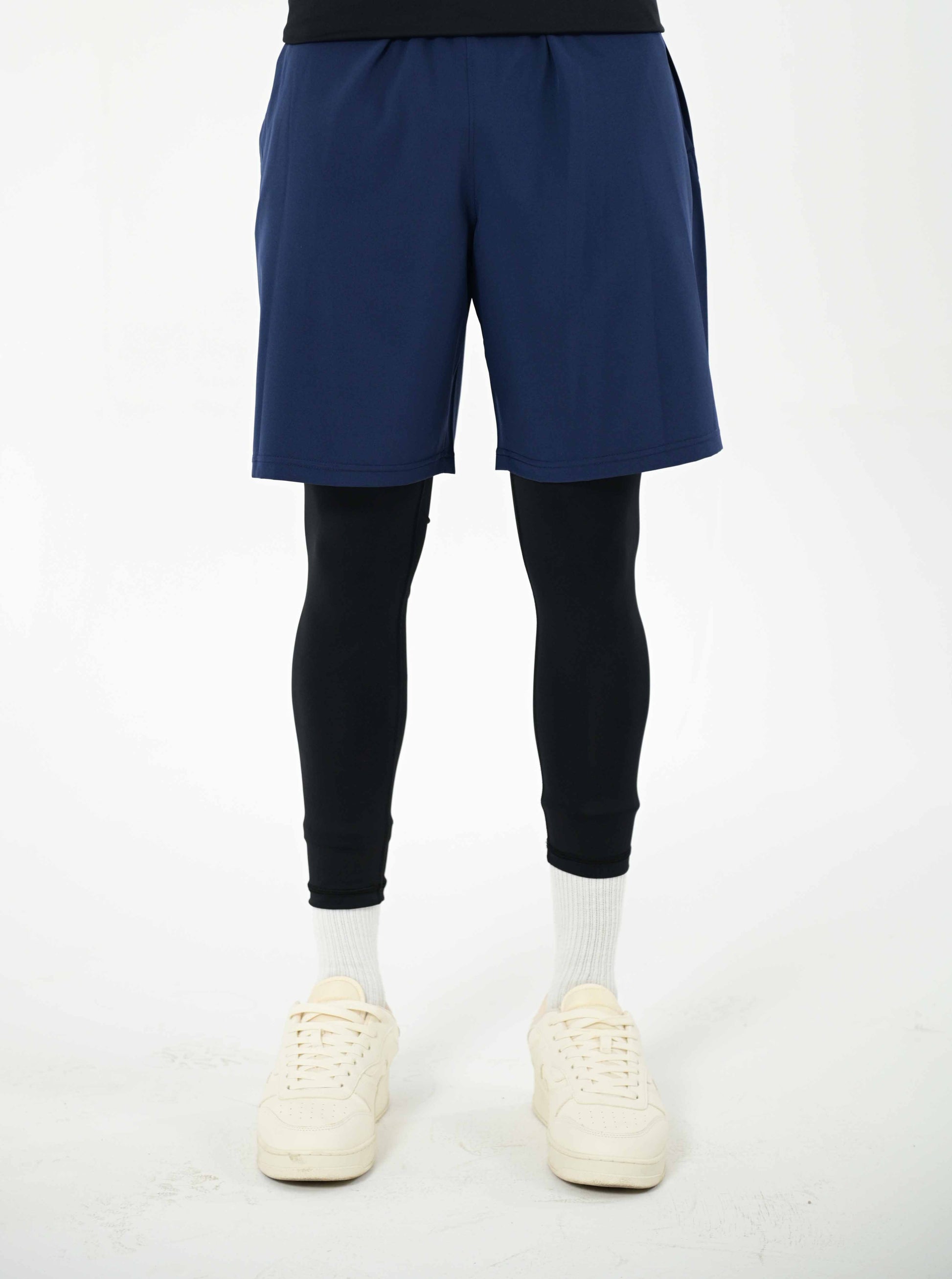 men wearing blue shorts, black base layer, and white sneakers on a white background