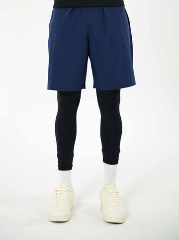 men wearing blue shorts, black base layer, and white sneakers on a white background